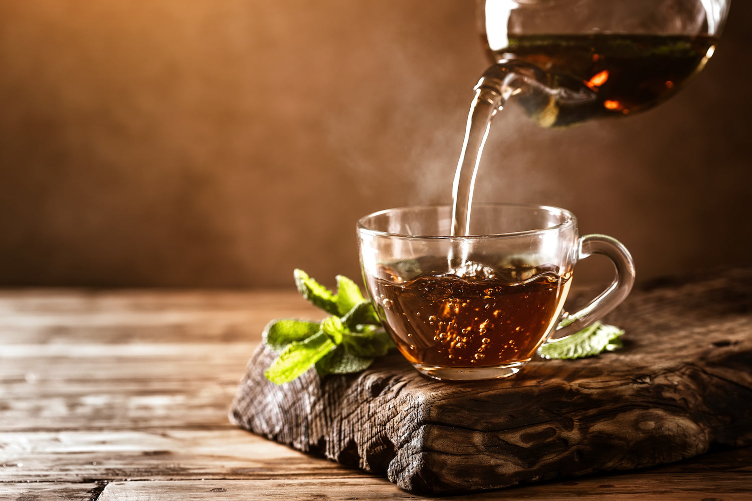 black tea being poured into a glass cup